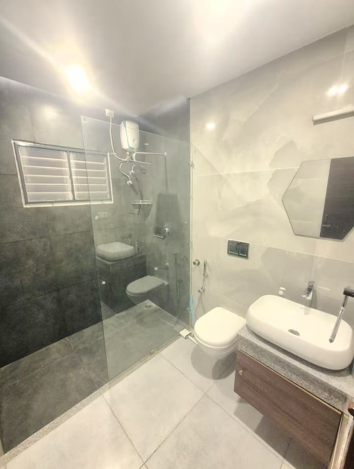 The same bathroom showing the glass shower enclosure, wall-hung toilet and vanity, with separated wet and dry areas