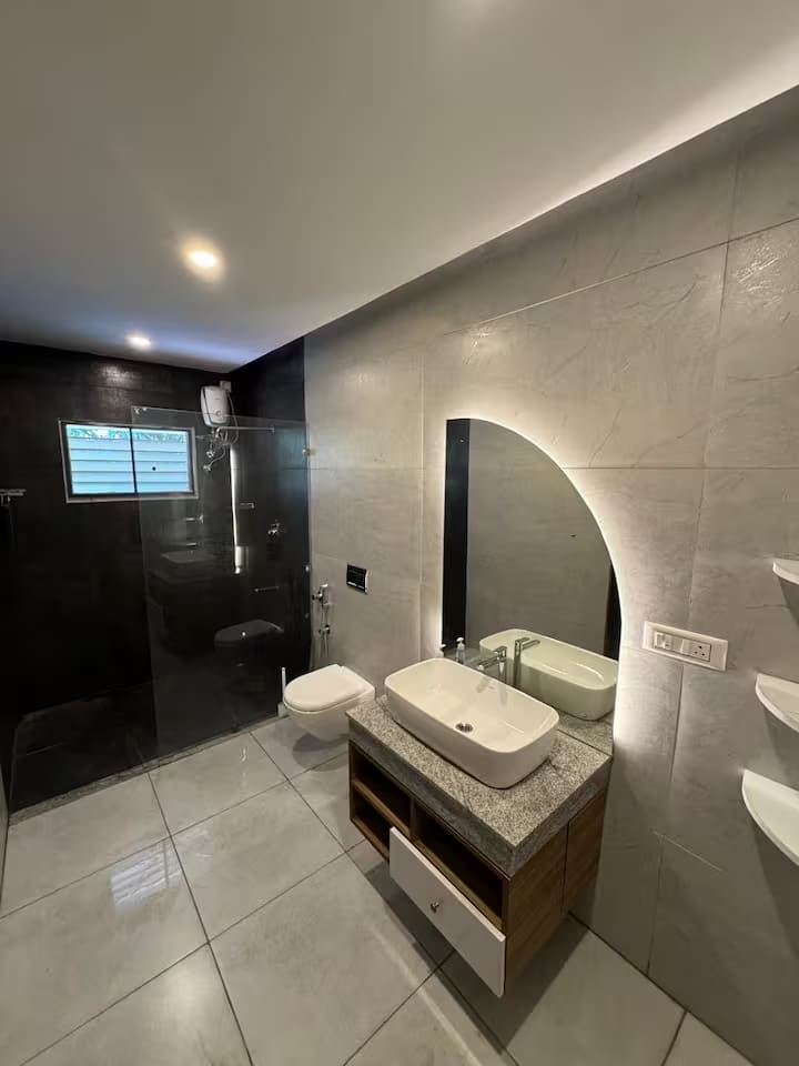 The larger upstairs en-suite, with a black feature wall, arched mirror and stone vanity