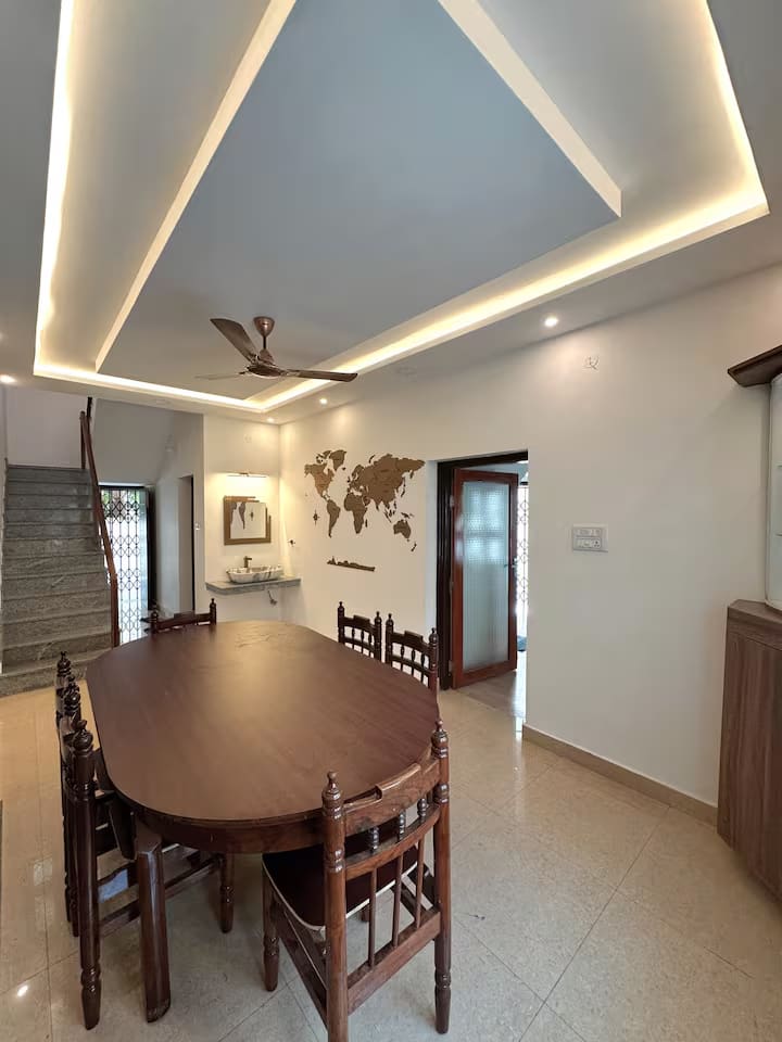The oval dining table seating eight, beneath a recessed cove-lit ceiling with a wooden world map on the wall