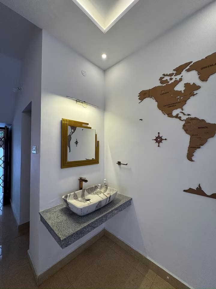 A washbasin on a granite counter beside the world map wall, on the way through to the dining room