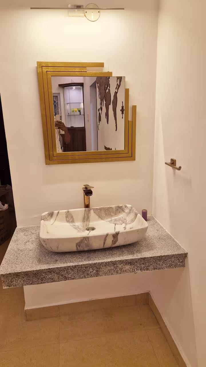 Marble vessel basin on a granite counter below a gold-framed mirror