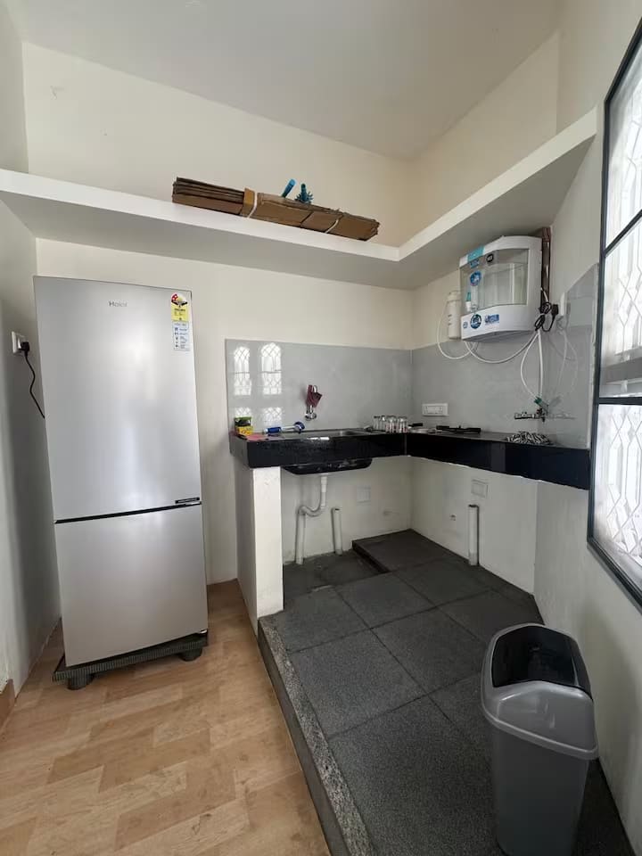 The kitchen with a tall refrigerator, granite worktop, microwave and electric stove
