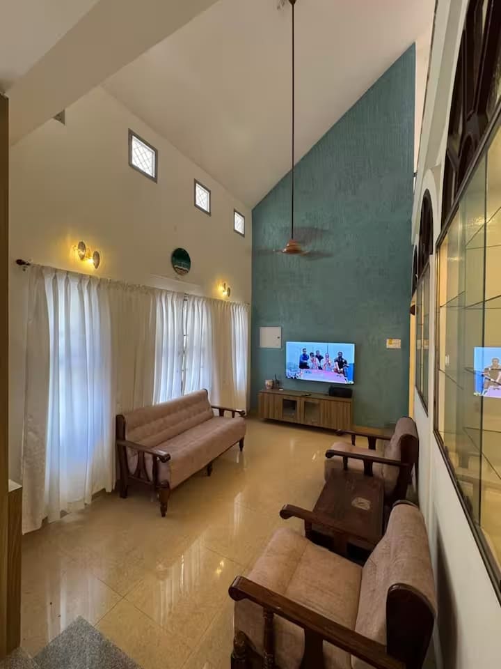 The living room seen from the far end, showing the full height of the ceiling and the tall curtained windows