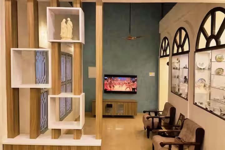 Open timber shelving beside the television, dividing the living room from the entrance hall