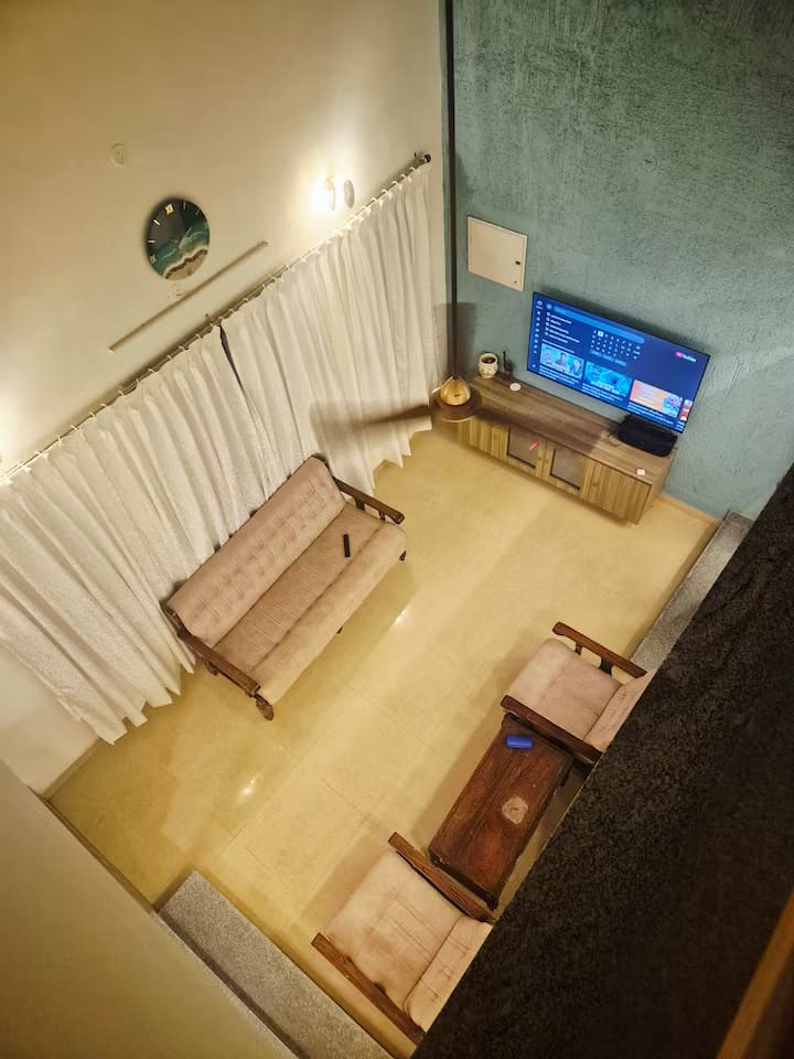 The living room from above, showing the seating, bench and television against the teal wall